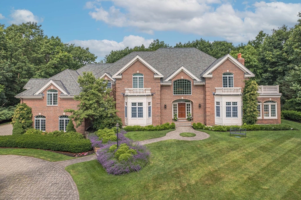 a front view of a house with a garden and trees
