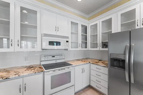 a kitchen with granite countertop white cabinets and white appliances