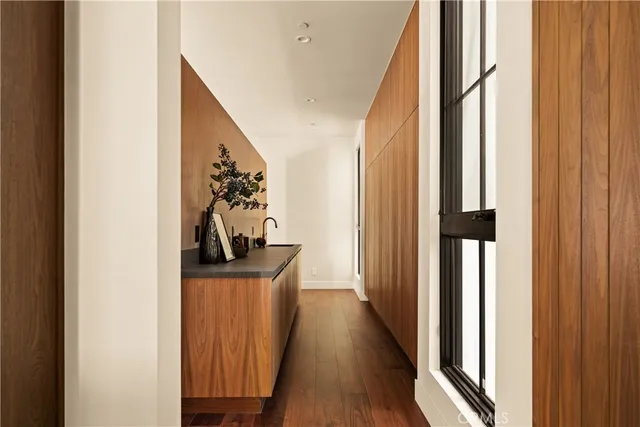 a view of a hallway with wooden floor and a bathroom
