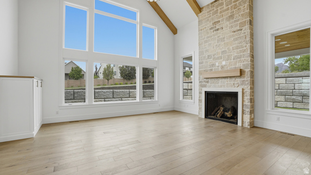 1682 North 1950 W Street, Unit 9 Provo, UT 84604 - Photo 18 of 84 Vaulted living space featuring a floor-to-ceiling stone fireplace with a wood mantle, wood-finish flooring, exposed ceiling beams, and a built-in cabinet with a wood countertop