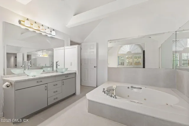 a bathroom with a tub a sink and mirror