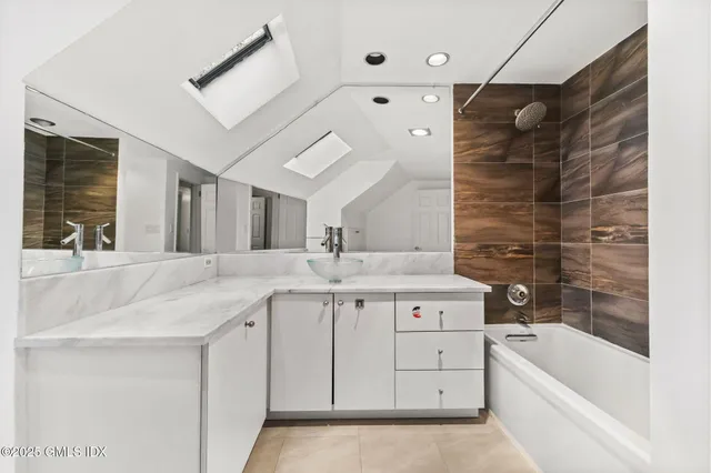 a spacious bathroom with a granite countertop sink a mirror a bathtub and shower