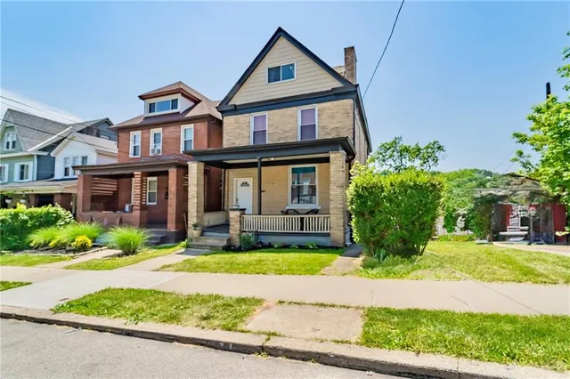 a front view of a house with yard and green space