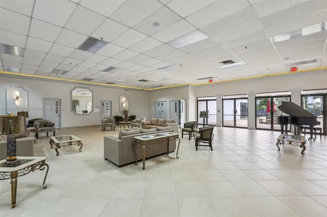 a view of a white house in front of a big yard with plants and large trees