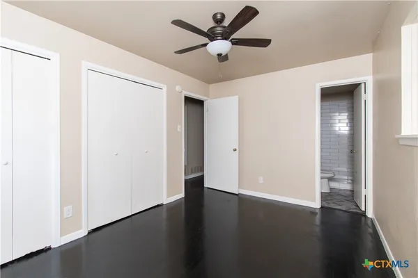 an empty room with wooden floor and a ceiling fan