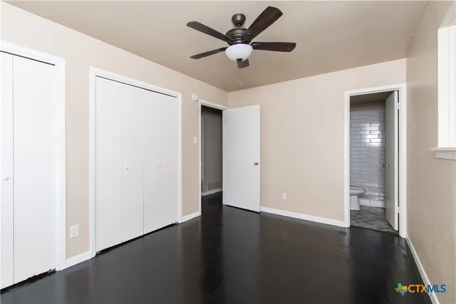 an empty room with wooden floor and a ceiling fan