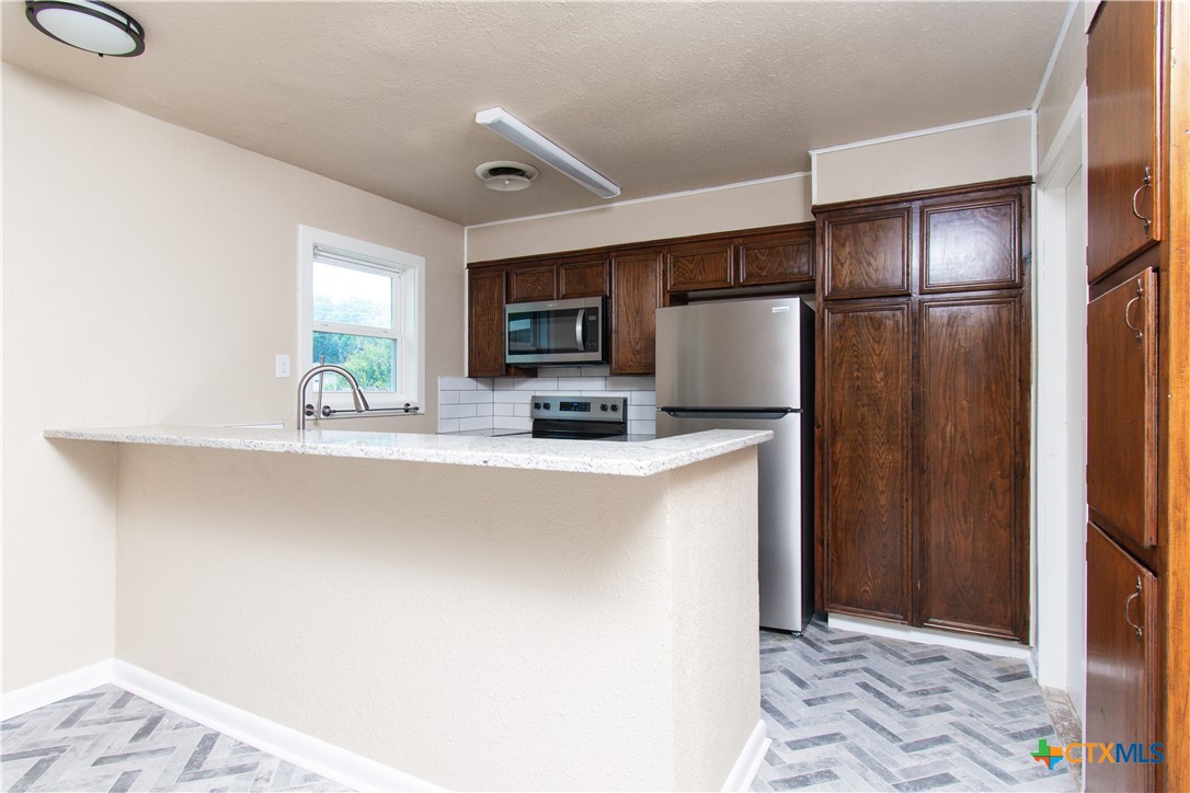 1312 Stephen Street Killeen, TX 76549 - Photo 6 of 19 a kitchen with stainless steel appliances a refrigerator sink and microwave