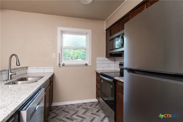 a kitchen with stainless steel appliances granite countertop a sink stove and refrigerator