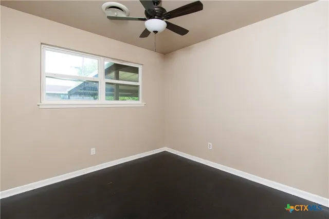 an empty room with a window and a fan