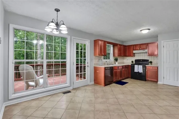 a large kitchen with kitchen island granite countertop a large counter top stainless steel appliances a chandelier and cabinets
