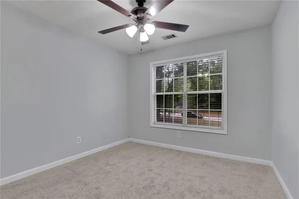 an empty room with a window and a fan