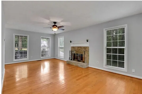 a view of an empty room with windows and a fireplace