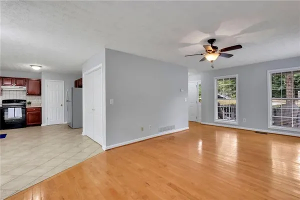 a view of an empty room with a window and a kitchen
