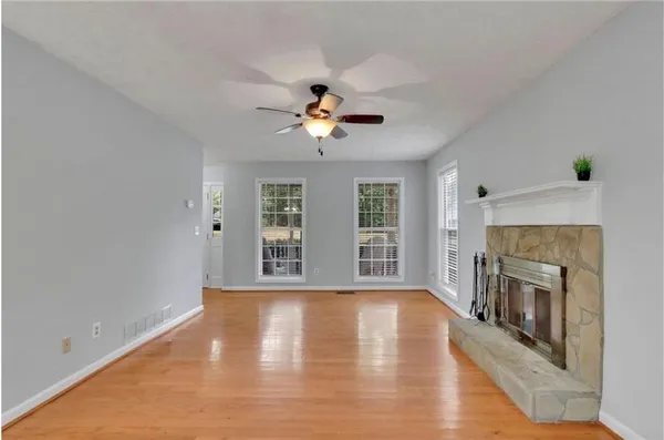 a view of an empty room with wooden floor fireplace and a window
