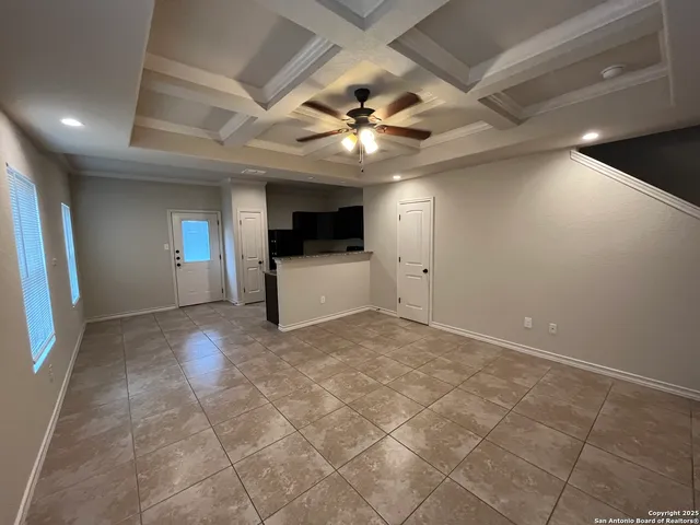 a view of an empty room with a fireplace and a ceiling fan