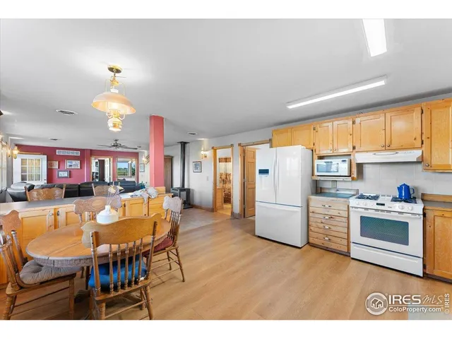 a living room with furniture a kitchen island a stove a refrigerator a dining table and chairs with wooden floor