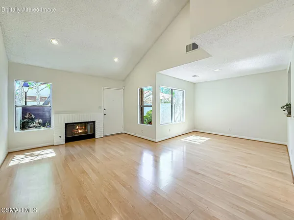 an empty room with wooden floor fireplace and windows