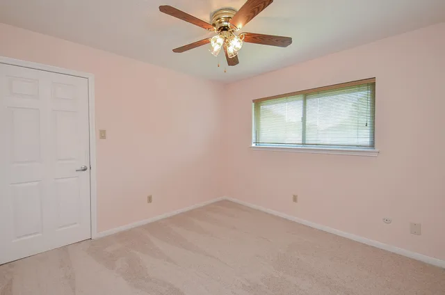 an empty room with a window and a fan