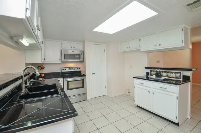 a kitchen with granite countertop a stove sink and cabinets