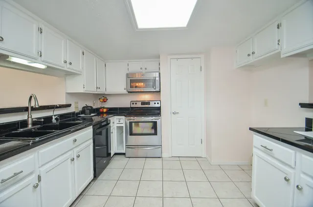 a kitchen with white cabinets and appliances