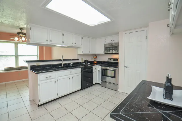 a kitchen with granite countertop white cabinets and white appliances