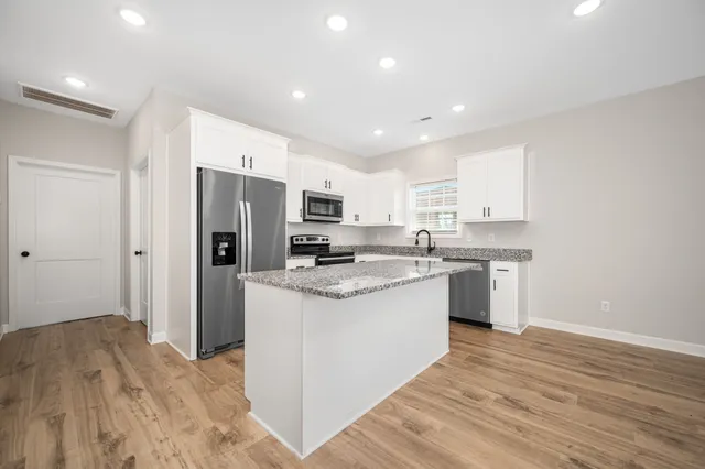 a kitchen with a sink a refrigerator a window and cabinets