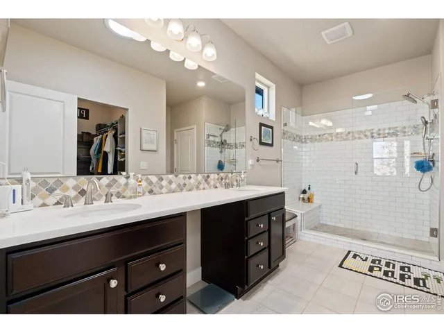 a bathroom with a sink double vanity granite tub shower and a mirror