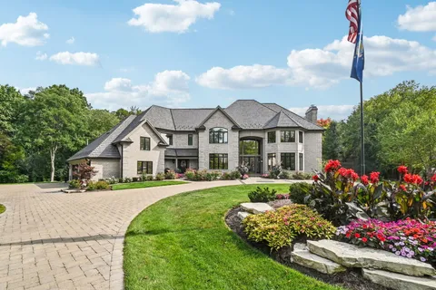 a front view of a house with a yard and fountain in middle