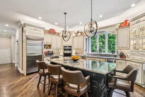 a kitchen with stainless steel appliances granite countertop a stove a kitchen island a dining table and chairs in the kitchen