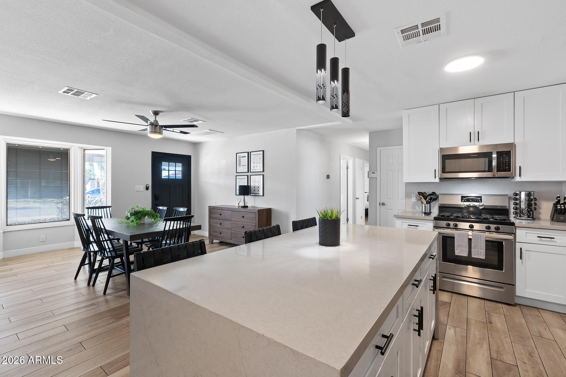 726 West 19th Street Tempe, AZ 85281 - Photo 25 of 40 a kitchen with stainless steel appliances kitchen island granite countertop a stove a sink a dining table and chairs with wooden floor