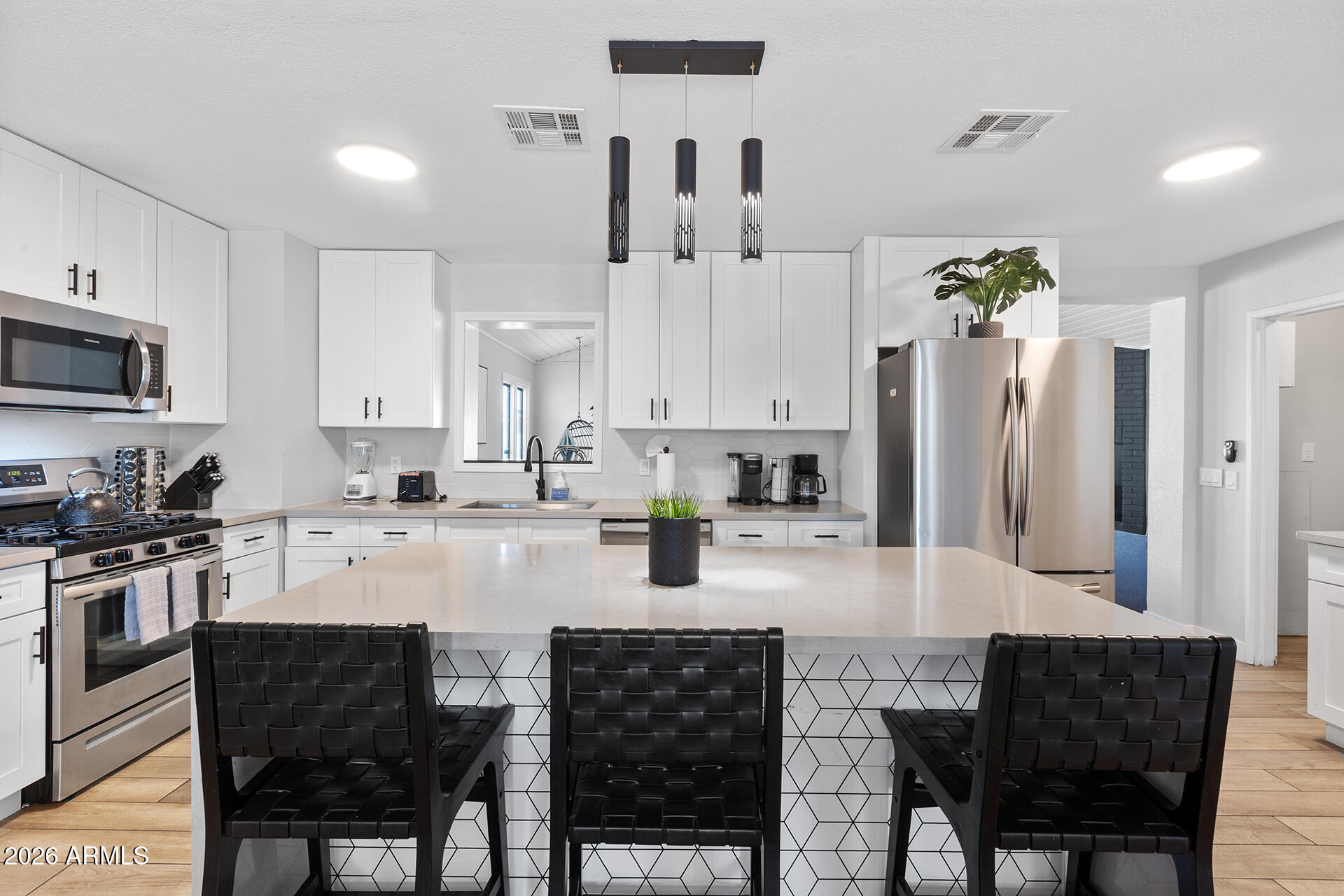 726 West 19th Street Tempe, AZ 85281 - Photo 3 of 40 a kitchen with stainless steel appliances a dining table chairs refrigerator and sink