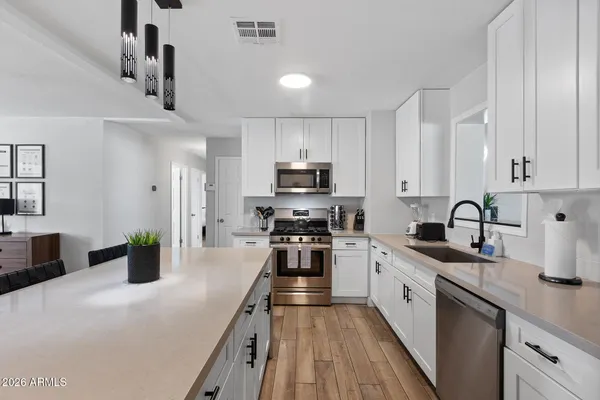 a kitchen with a sink a counter top space stainless steel appliances and cabinets