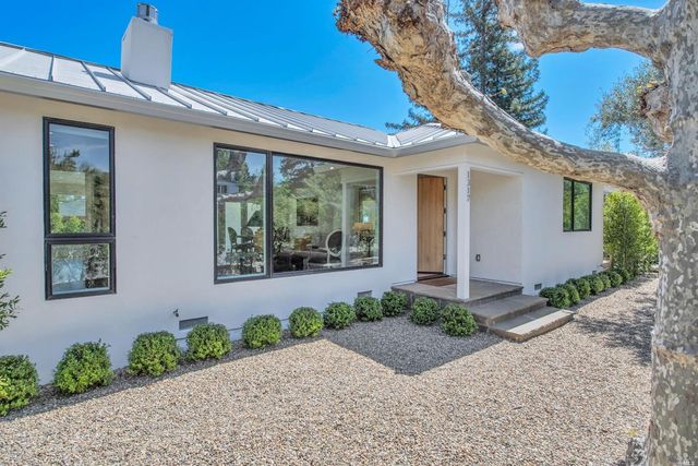a front view of a house with a yard and potted plants
