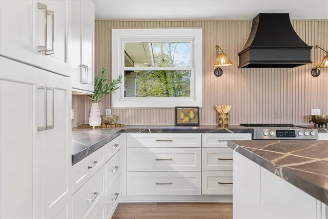 a kitchen with granite countertop white cabinets and window