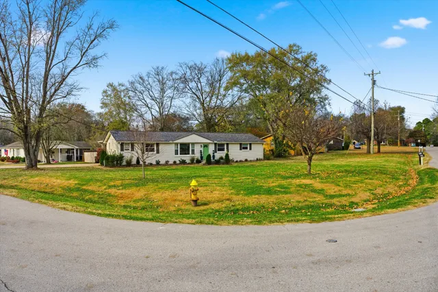 a view of a house with a big yard and palm trees