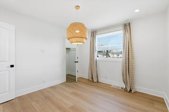an empty room with wooden floor and mirror