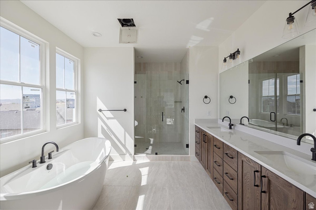 7189 South Sage Road, Unit 214 West Jordan, UT 84081 - Photo 16 of 29 Bright bathroom featuring a freestanding tub, glass-enclosed shower, and a dual vanity with wood-finish cabinetry