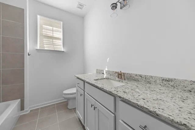 a bathroom with a granite countertop sink a toilet and a mirror