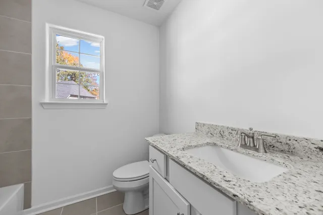 a bathroom with a granite countertop sink and a toilet