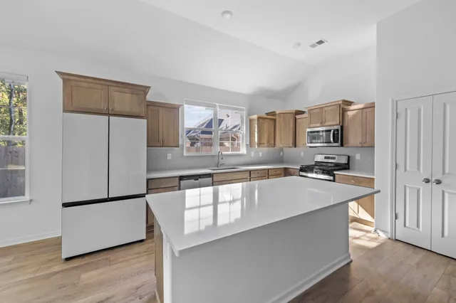 a large kitchen with stainless steel appliances a refrigerator and a stove top oven