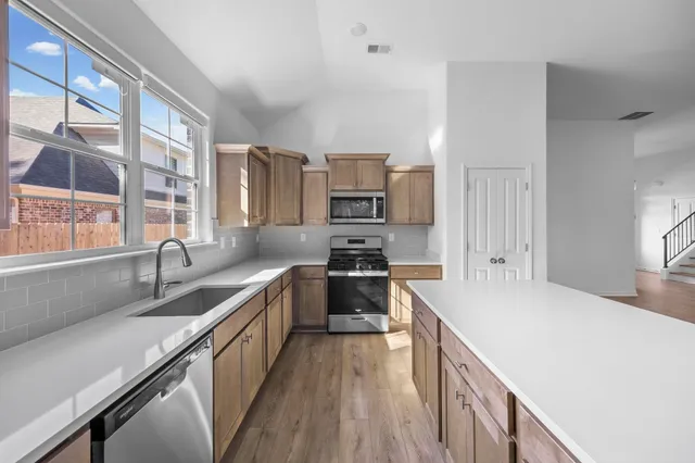 a kitchen with stainless steel appliances granite countertop a sink dishwasher stove and refrigerator