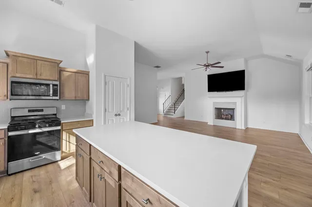 a living room with stainless steel appliances a fireplace a flat screen tv and a refrigerator