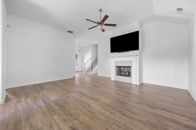 a view of an empty room with wooden floor and a fireplace