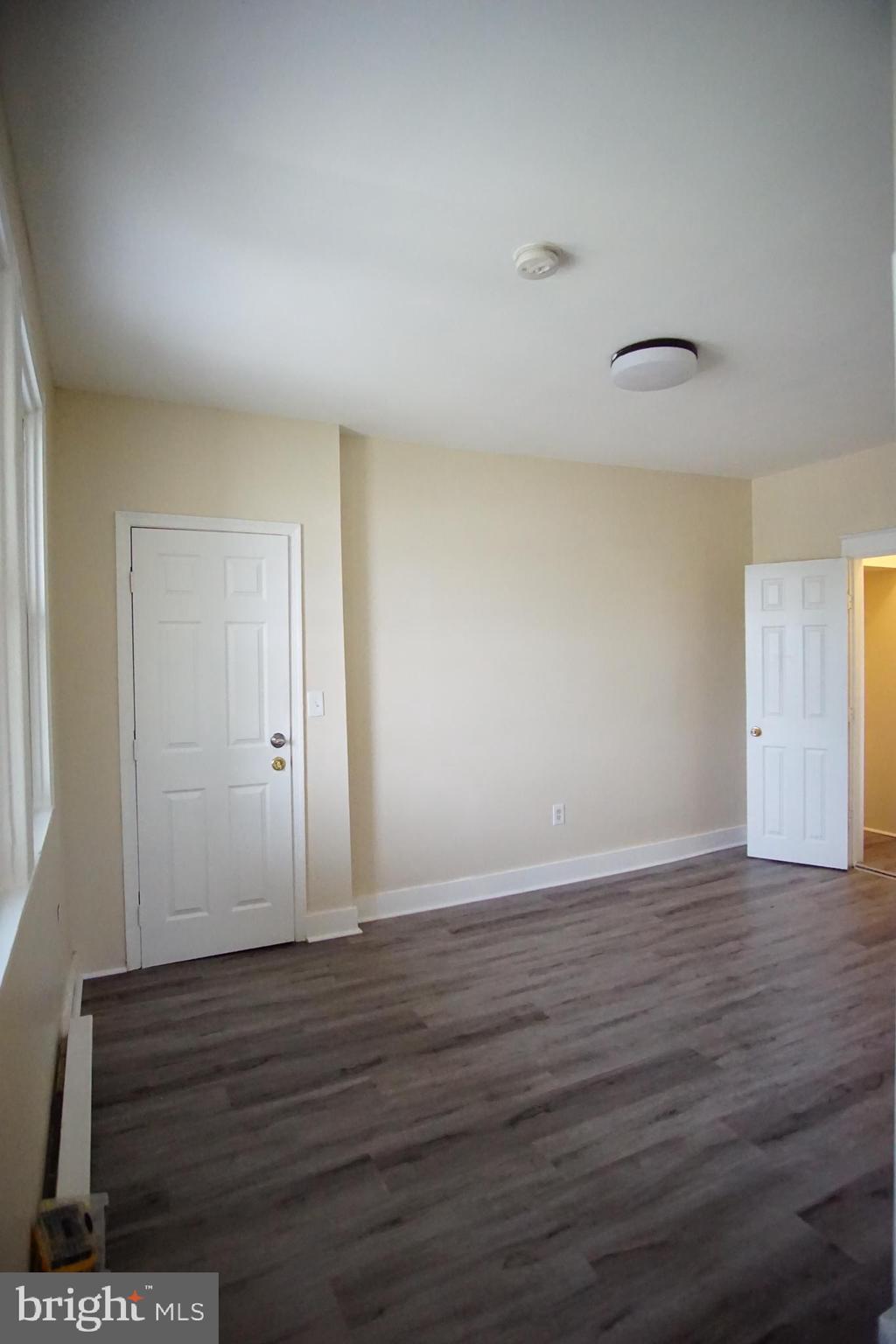 5200 Ballman Avenue, Unit 3 Baltimore, MD 21225 - Photo 12 of 17 a view of an empty room with wooden floor and a window