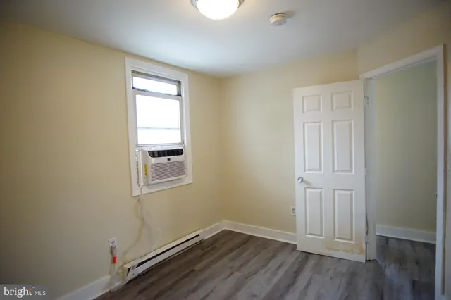 an empty room with wooden floor cabinet and windows