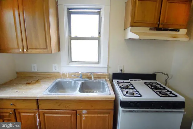 a kitchen with a sink a stove cabinets and a window