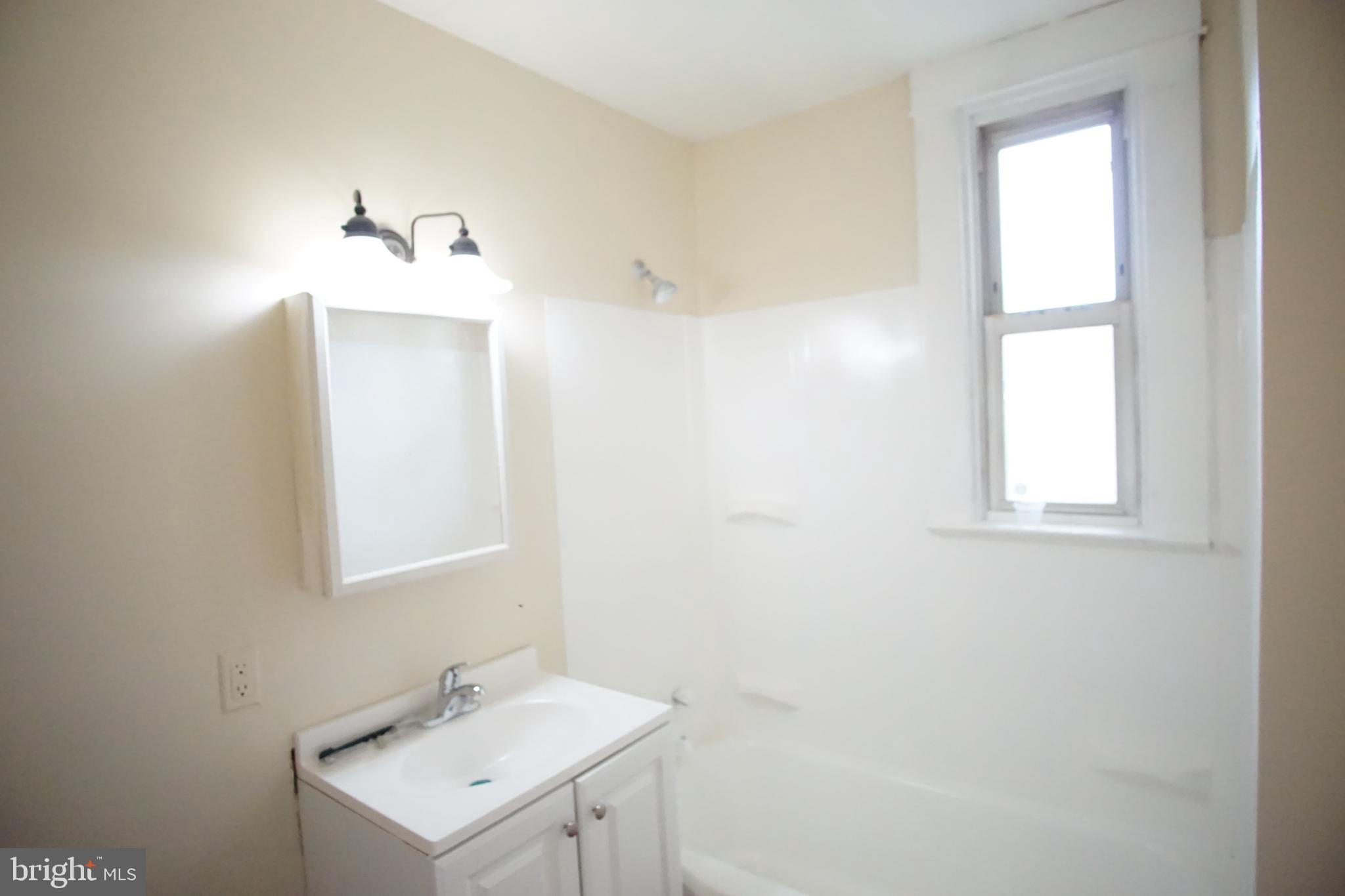5200 Ballman Avenue, Unit 3 Baltimore, MD 21225 - Photo 4 of 17 a bathroom with a sink a mirror and a window