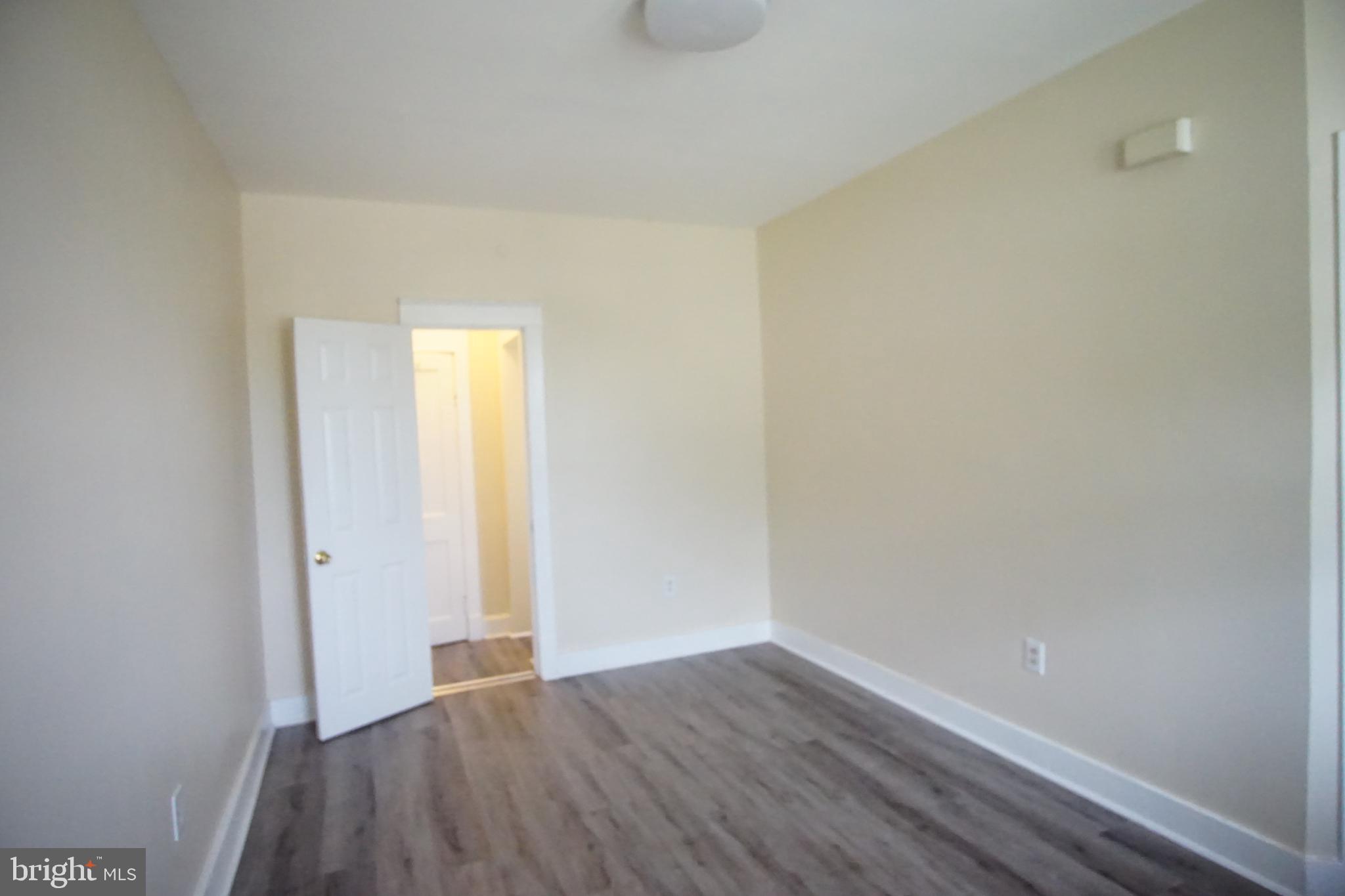 5200 Ballman Avenue, Unit 3 Baltimore, MD 21225 - Photo 6 of 17 a view of an empty room with wooden floor and a window