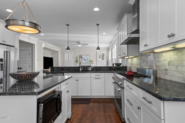 a kitchen with stainless steel appliances granite countertop a kitchen island hardwood floor sink stove and wooden cabinets