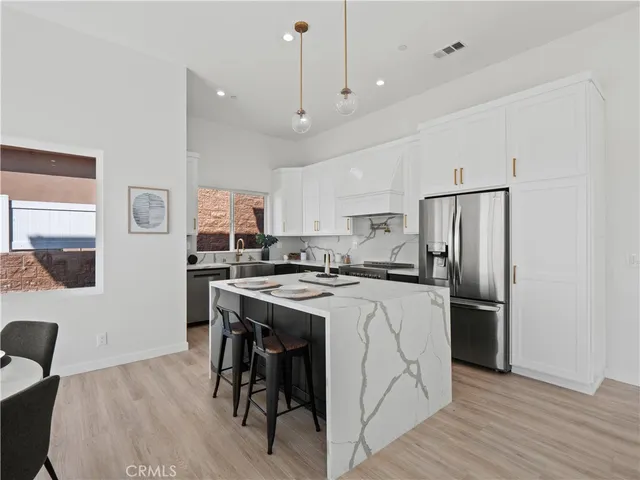 a kitchen with stainless steel appliances granite countertop a refrigerator a stove a sink dishwasher and a refrigerator with wooden floor